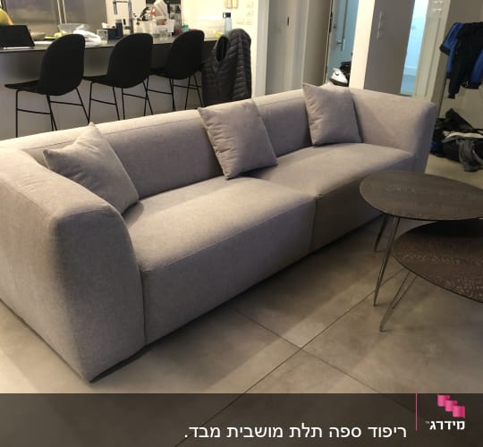 ספה אפורה עם כריות ושולחנות עגולים